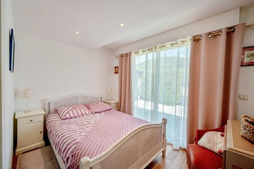 une chambre avec un lit et une grande fenêtre dans l'établissement La Cigale - T2 de plain pied avec piscine partagée, à Puget-Ville