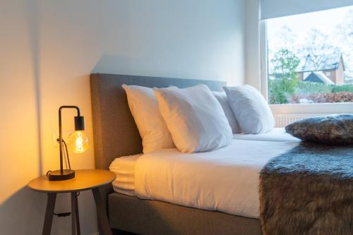 een slaapkamer met een bed met witte kussens en een raam bij 't Achterhuis (2 persons) in Otterlo