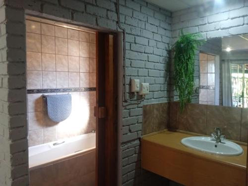 ein Badezimmer mit einem Waschbecken und einer Badewanne in der Unterkunft Kameelboom Lodge in Vryburg