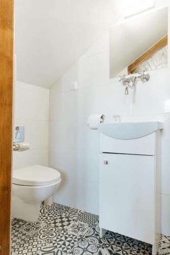 a white bathroom with a toilet and a sink at Pokoje Gościnne Cheval in Krakow