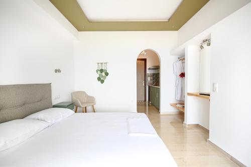 a white bedroom with a bed and a chair at Makis Sea View Studios in Skiathos Town