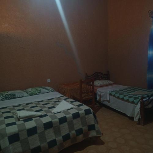 a room with two beds in a room at Hostel la palmeraie merzouga in Merzouga