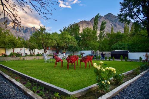 a group of red chairs on a lawn with mountains in the background at Hotel Travel Lodge in Skardu