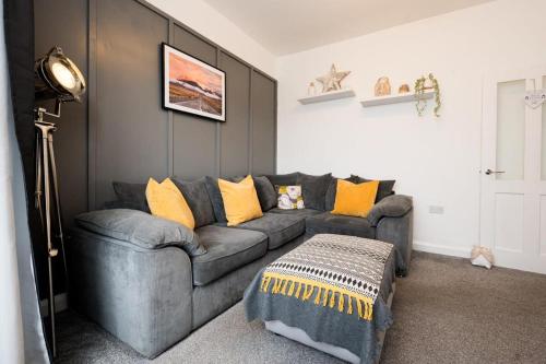 uma sala de estar com um sofá cinzento com almofadas amarelas em Dunraven by StayStaycations em Port Talbot