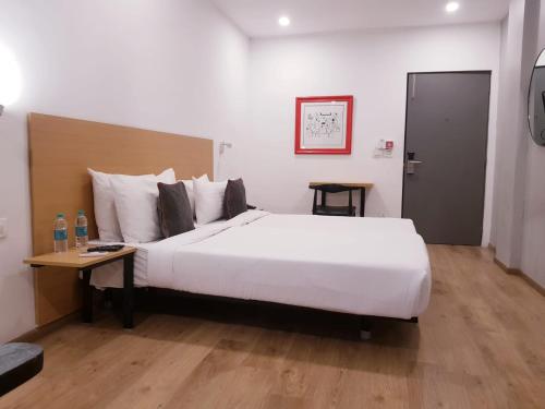 a hotel room with a large white bed and a table at Hotel Samrat, Mumbai in Mumbai