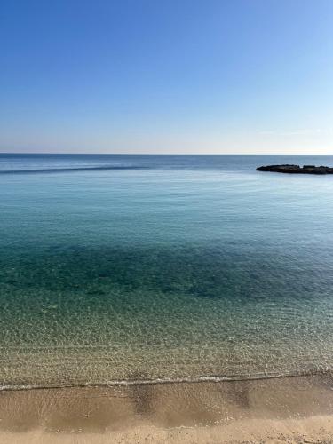 a large body of water with a sandy beach at Innesto Rooms - Monopoli in Monopoli