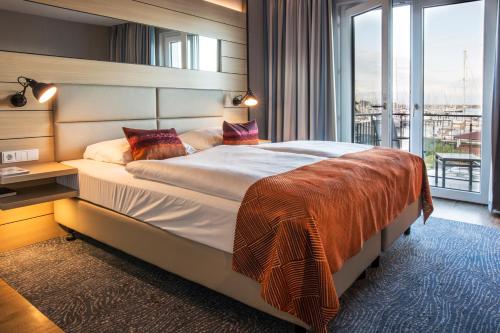 a bedroom with a large bed and a large window at Hafenhotel Meereszeiten in Heiligenhafen