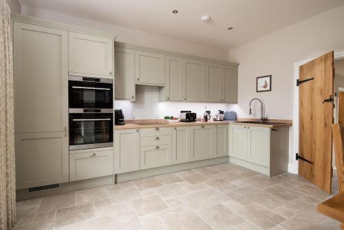 a kitchen with white cabinets and a tile floor at Granary View, Brockmill Farm in Berwick-Upon-Tweed
