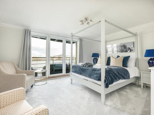 a bedroom with a white canopy bed and a chair at The View Greenwich - Luxury River Thames Apartment in London