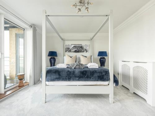 a bedroom with a white canopy bed with pillows at The View Greenwich - Luxury River Thames Apartment in London