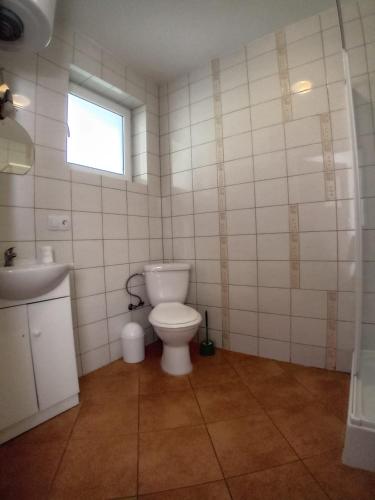 a bathroom with a toilet and a sink and a window at Domimat-Lila in Dębki