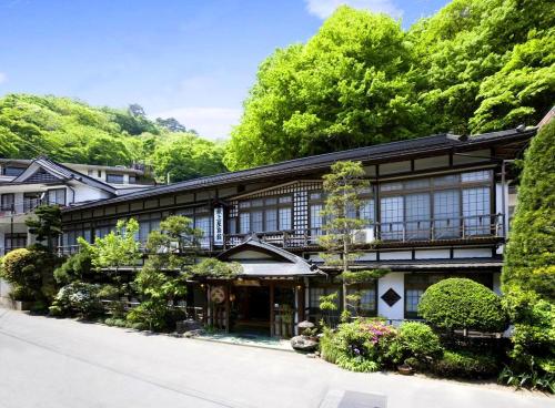 un vieux bâtiment noir et blanc avec des arbres dans l'établissement Mogamiya Ryokan, à Shiroishi