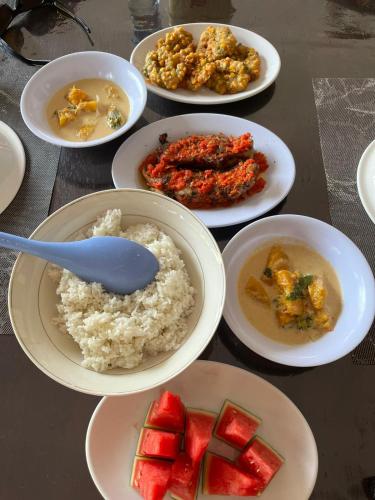 a table topped with plates of food with rice and fruit at EL Homestay Bunaken in Bunaken