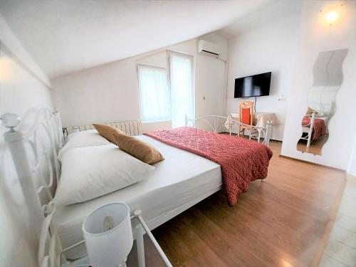 a bedroom with a white bed with a red blanket at Guesthouse Cecilia 2 in Malinska