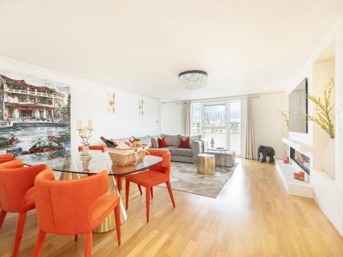 a living room with a table and orange chairs at The View Greenwich - Luxury River Thames Apartment in London