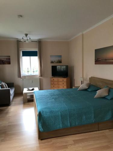 Un dormitorio con una cama, un sofá y un televisor. en Haus Nicolai FeWo 8, en Baabe