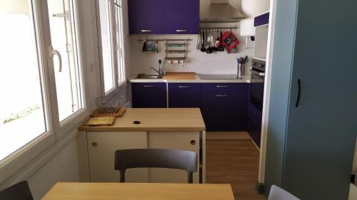 une petite cuisine avec des placards bleus et une table dans l'établissement Studio à Sables d'Or avec vue sur mer - Wi-fi haut débit - Parking - Parc privé, à Fréhel