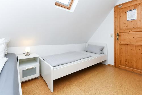 a small bed in a room with a door at Pension Hohaus in Neuharlingersiel