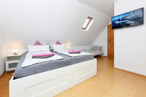 a white bedroom with a large bed with pink pillows at Pension Hohaus in Neuharlingersiel