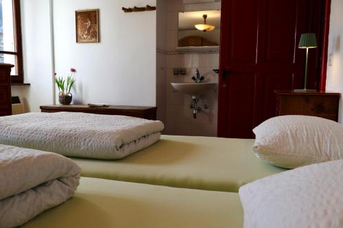 two beds in a room with a sink and a bathroom at Antica Osteria Dazio in Fusio