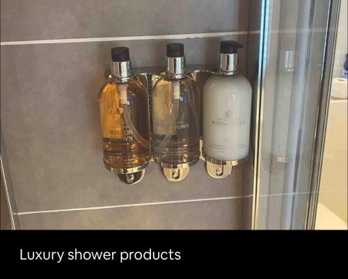 una mensola con quattro bottiglie di prodotti per la doccia di lusso di Cathedral Coach House a Lichfield