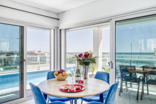 - une salle à manger avec une table, des chaises et des fenêtres dans l'établissement Ocean Chic by the Beach, à Albufeira