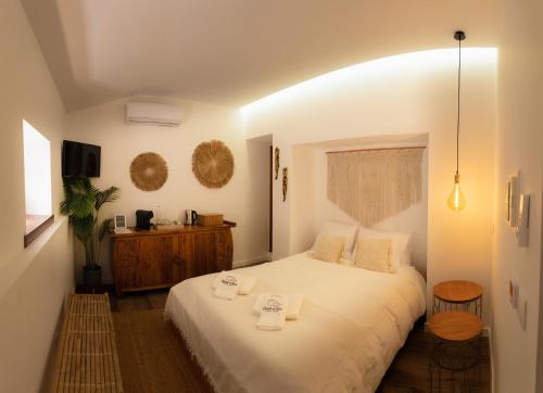 um quarto com uma cama branca com duas toalhas em Quinta da Relva - Soulful House em Mafra