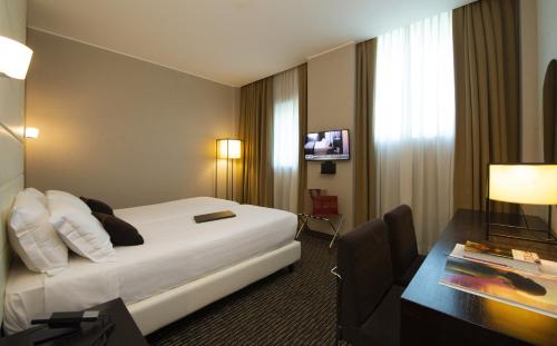 Pokój hotelowy z łóżkiem i biurkiem w obiekcie H2C Hotel Milanofiori w mieście Assago