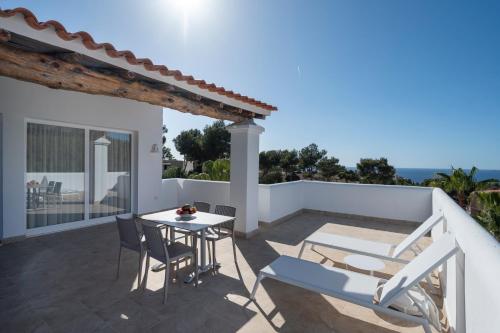 a patio with a table and chairs on a balcony at Apartamentos Blanco Sol in Cala Vadella