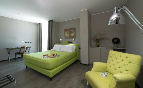 a bedroom with a green bed and a chair at H2C Hotel Milanofiori in Assago