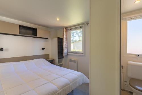 - une chambre avec un lit, une fenêtre et un lavabo dans l'établissement Mh 122 Ronce les bains, à La Tremblade