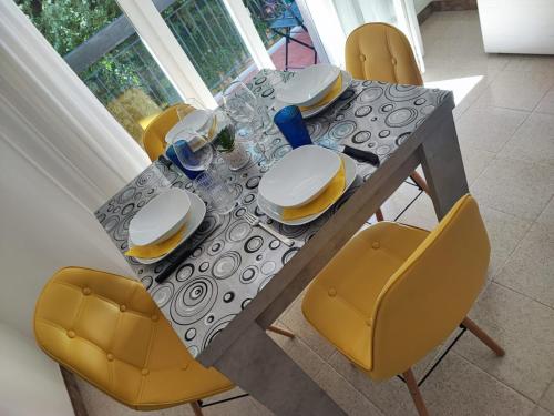 een eettafel met gele stoelen en een tafel met borden bij Casa Vacanza Orchidea in Trieste
