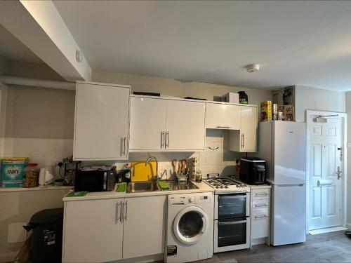 a kitchen with white cabinets and a washing machine at Central London, Free Parking in London