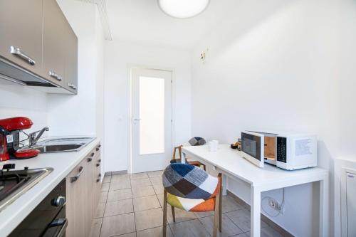 eine weiße Küche mit einem Tisch und einer Mikrowelle in der Unterkunft Jasmine Luxury Aviatiei in Herăstrău