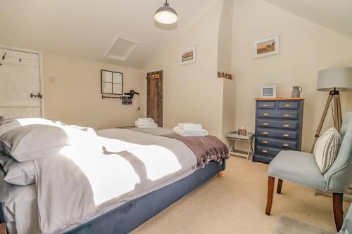 a bedroom with a bed and a chair and a dresser at Quaint 2 bed cottage near North Norfolk Coast - Harpers Cottages in Syderstone