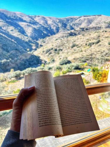 a person holding a book in front of a window at Casa Alfurán in Alfornón