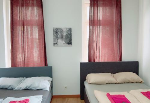 twee bedden in een kamer met rode gordijnen bij Sam Apartment 19A in Wenen