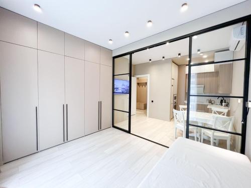 1 dormitorio con armarios blancos y pared de cristal en Фешенебельные апартаменты в ЖК 4YOU, en Baganashyl