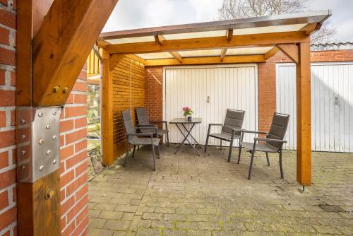 a patio with chairs and a table under a wooden pergola at Ferienwohnung Krempermoor 2 in Krempermoor