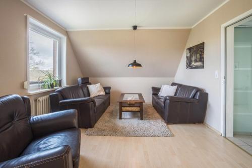 a living room with two leather couches and a table at Ferienwohnung Krempermoor 2 in Krempermoor