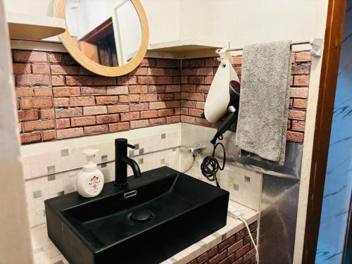 een badkamer met een zwarte wastafel en een spiegel bij 温泉街の入り口にあるゲストハウス SLOW HOUSE yugawara in Yugawara