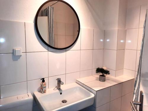 ein weißes Badezimmer mit einem Waschbecken und einem Spiegel in der Unterkunft City-Wohnung mit Ausblick in Bochum