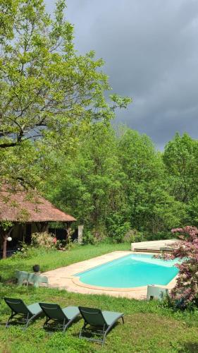 - une piscine entourée de chaises dans l'herbe dans l'établissement Le Manoir du Moulin de Madame, à Villeneuve-sur-Lot