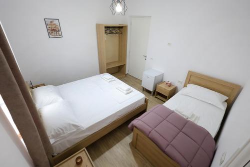 a small bedroom with two beds and a purple ottoman at Vila Vreko in Berat