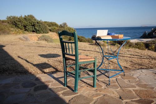 een tafel en een stoel naast de oceaan bij Apiliotis sunrise beach villa in Ligaridia