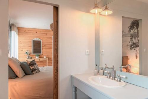 La salle de bains est pourvue d'un lavabo et d'un lit avec un miroir. dans l'établissement La Grange du Coulin, à Onesse-et-Laharie