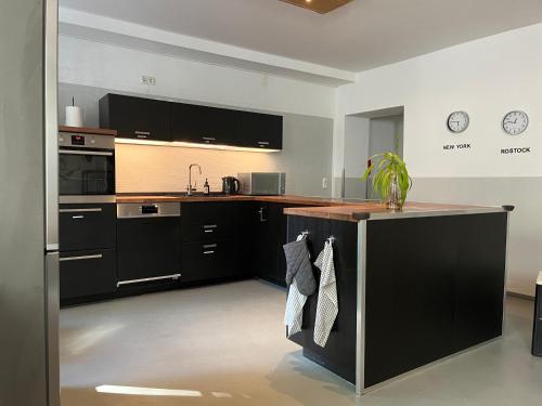 a kitchen with black cabinets and a counter top at Blue Doors Hostel Altstadt in Rostock