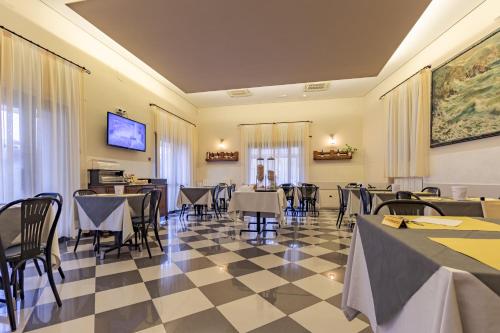 um restaurante com mesas e cadeiras num piso de xadrez em Albergo La Marina B&B em Deiva Marina