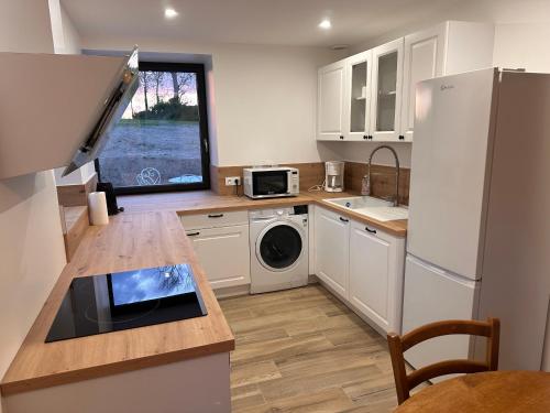 une cuisine avec des armoires blanches, un évier et un réfrigérateur dans l'établissement Gîte Cotentin Sweet Home, à Blosville