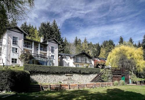 a large house with a stone wall in a yard at Alojamiento en Aldea Andina in San Carlos de Bariloche